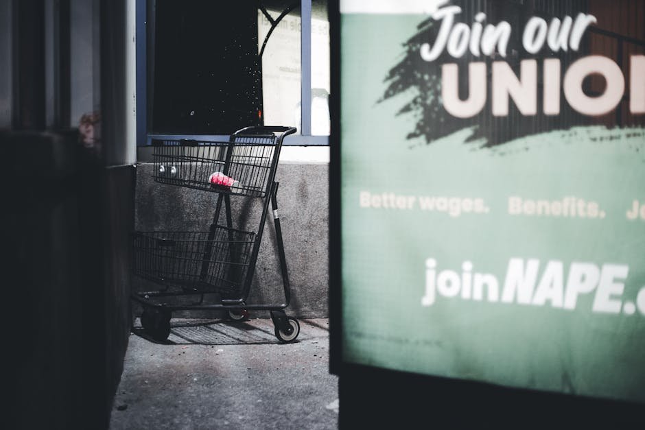 Dramatic urban scene featuring an empty shopping cart and a union sign at night.