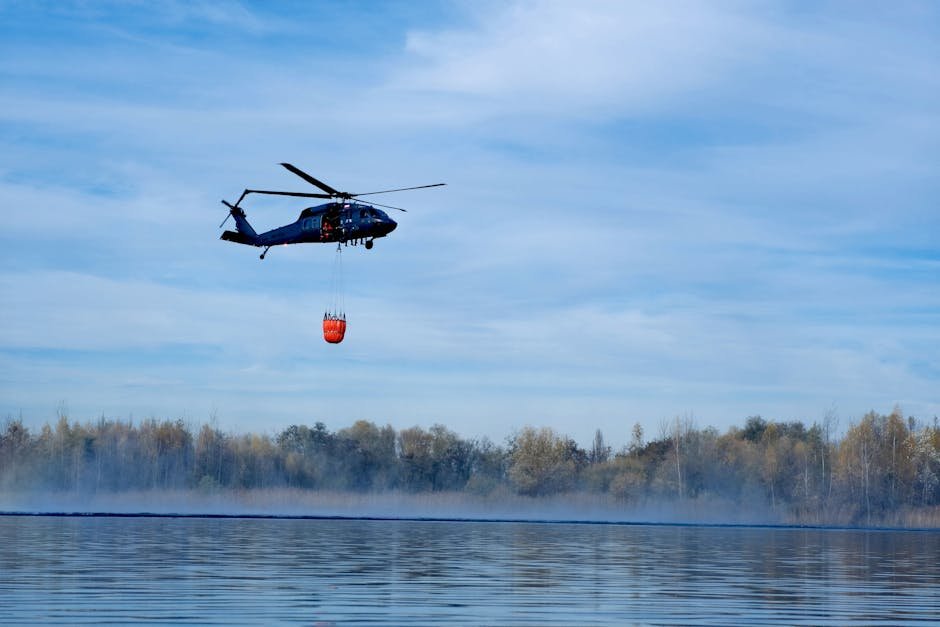A helicopter collects water from a lake for firefighting efforts on a clear day.